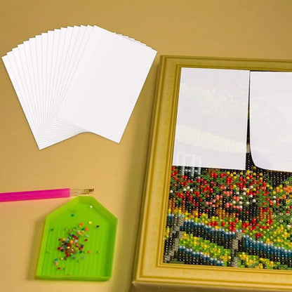 Afdekstickers gebruikt op deels voltooide diamond painting met gereedschap en kralen ernaast.